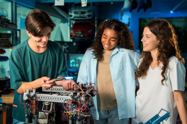Group of young people doing experiments in robotics in a laboratory using tools